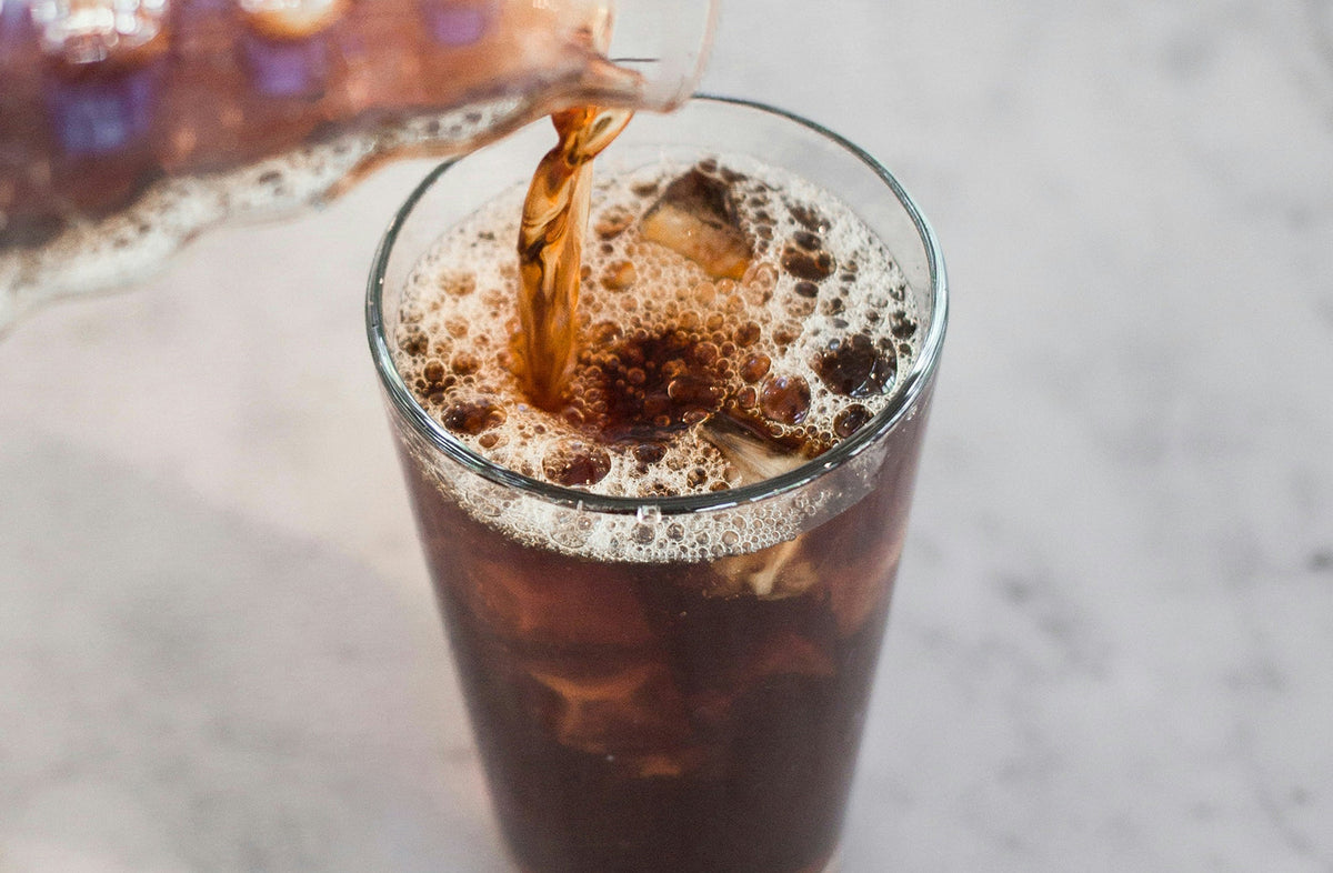 Cold brew coffee being poured over ice in a tall glass - Seattle Coffee Gear