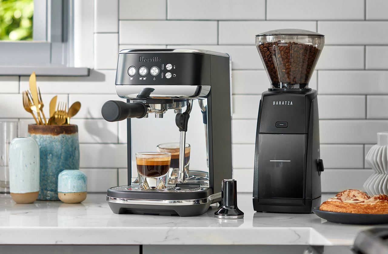 Black Breville espresso machine and Baratza grinder on a marble kitchen counter