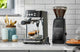Black Breville espresso machine and Baratza grinder on a marble kitchen counter