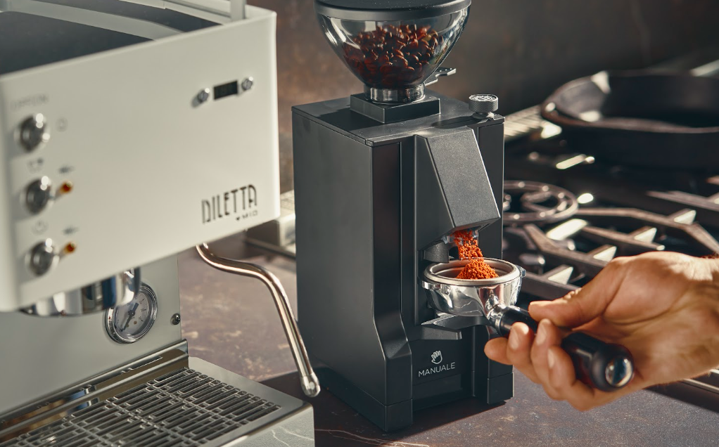 Electric espresso grinder dispensing fresh grounds into a portafilter beside a Diletta Mio espresso machine - Seattle Coffee Gear