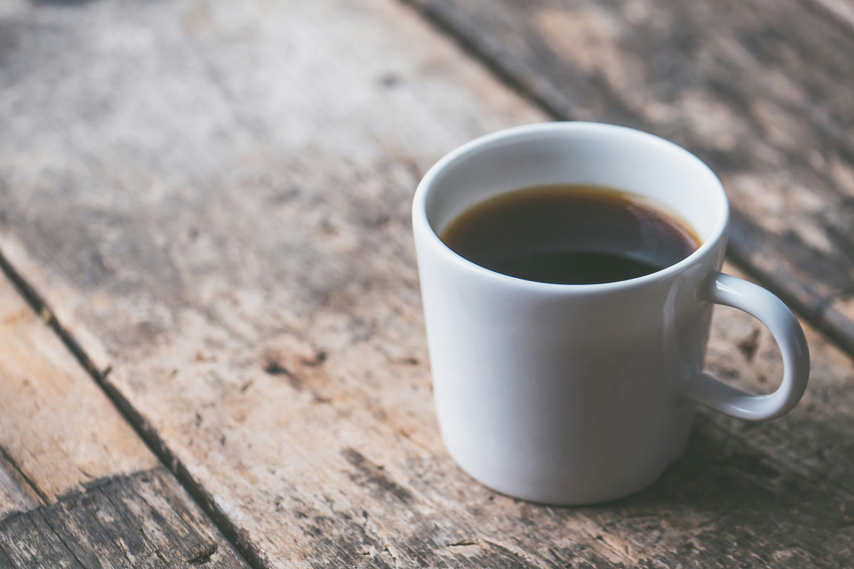 Coffee in a coffee cup on a wood plank - by Jessica Lewis - Seattle Coffee Gear